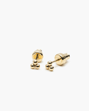 Pair of small gold stud earrings with a trio of tiny beads, featuring screw-back closures, laid on a white background.