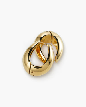 Pair of chunky gold huggie hoop earrings with a bold domed design, laid on a white background.