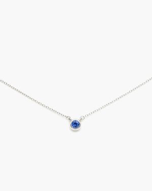 Silver necklace with a blue gemstone pendant on a plain white background.