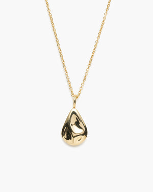 Close-up of gold necklace with a textured tear drop shaped pendant against a white background