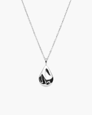 Close-up of silver necklace with a textured tear drop shaped pendant against a white background