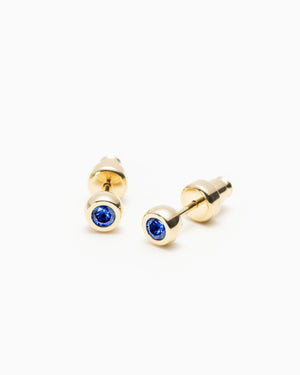 Pair of gold stud earrings with round blue gemstones