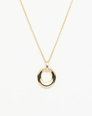 Close-up of thick gold circular pendant against a white background