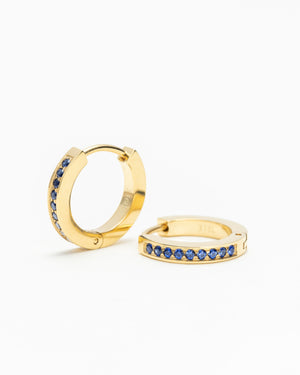 Pair of gold hoop earrings lined with blue gemstones, shown on a white background.