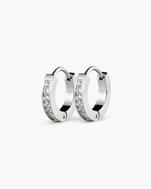 Pair of silver hoop earrings lined with white sapphire gemstones and engraved lettering, shown on a white background