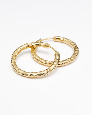 Gold hammered hoop earrings on a white background