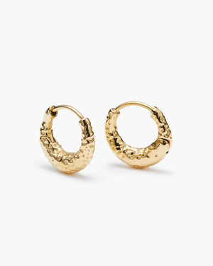 Gold hammered huggie earrings on a white background