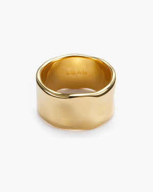 Wide gold band ring with an organic, irregular edge, engraved with a brand logo on the inner band, photographed on a plain white background.