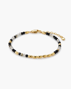Beaded bracelet with black, gray, and gold beads, featuring a lobster clasp closure and an adjustable extender chain with a small charm, photographed on a plain white background.