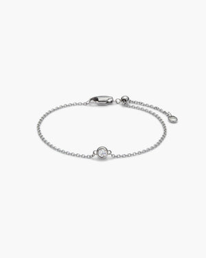 Delicate silver chain bracelet with a single gemstone charm, lobster clasp, and extender chain, laid flat on a white background.
