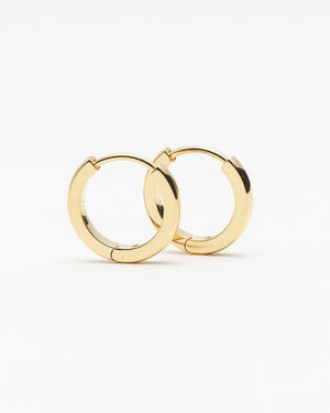 Pair of small gold huggie hoop earrings, laid on a white background.