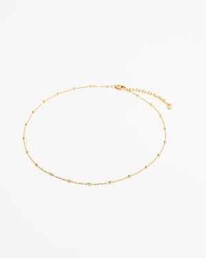 Gold beaded chain necklace on a white background